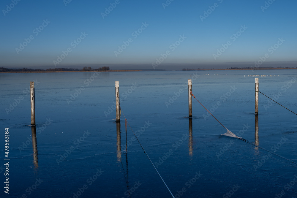 A view of empty docks in the winter. Blue water and a clear blue sky
