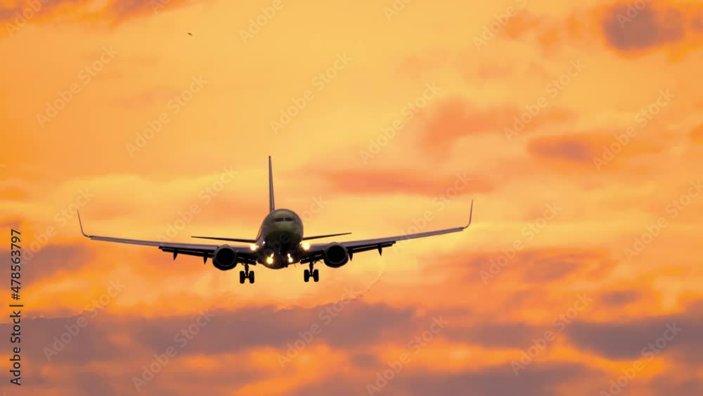 Jet plane flies at beautiful sunset for landing. Airplane silhouette approaching in golden sunset Jet plane flies at beautiful sunset for landing. Airplane silhouette approaching in golden sunset