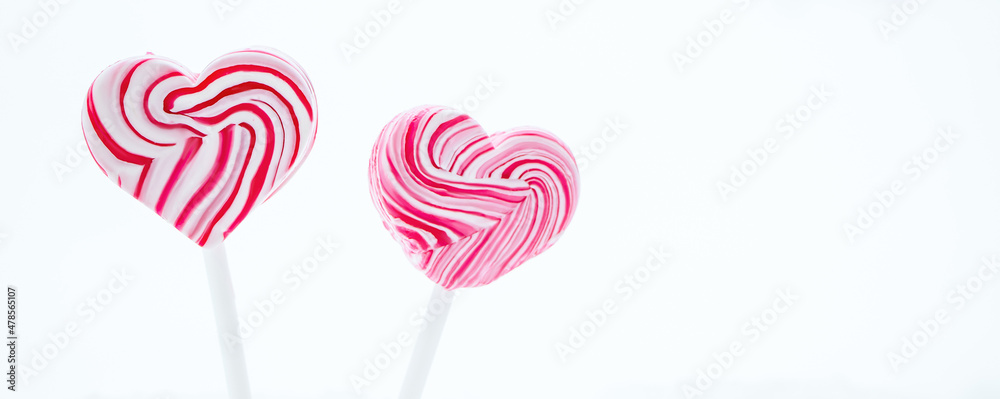 Two pink heart-shaped lollipop. Caramel candy on stick on white background. Sweet gift for valentines day.
