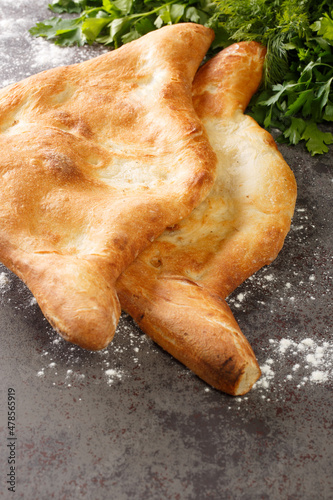 Shotis puri or shoti is a Georgian bread made with whole wheat flour, salt, water, and yeast close up on the table. Vertical photo