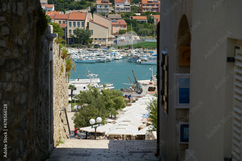 Blick durch eine enge Gasse auf den Hafen der Stadt Rab in Kroatien