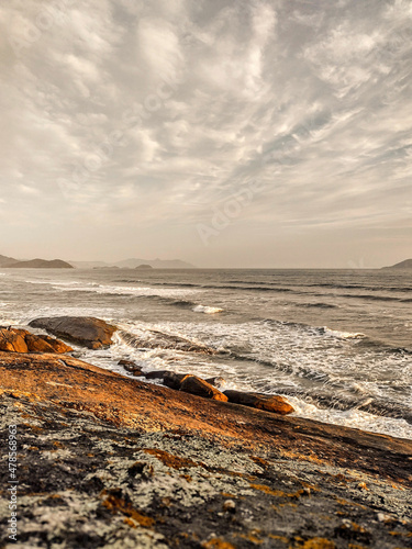 Seascape with rocks, clouds and hills.