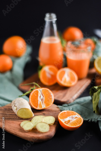 Frisch gepresster Orangensaft im Glas mit Citrusfrüchten auf dunklem Hintergrund. Fruchtiges Stillleben auf schwarzen Hintergrund mit frischen Früchten