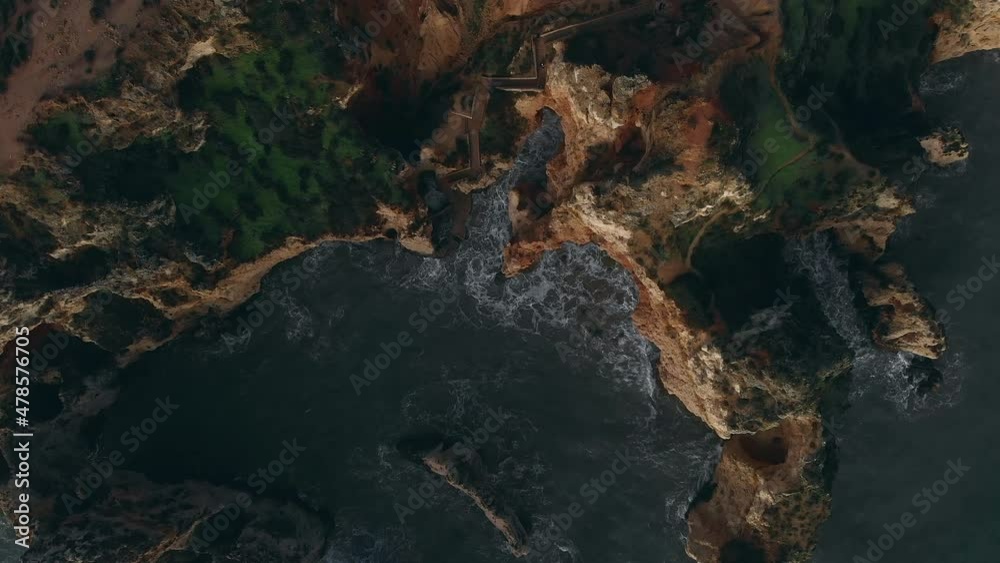 Aerial drone point of view raging ocean and Ponta da Piedade headland with group of rock formations yellow cliffs along limestone coastline, Lagos town, most famous touristic attractions of Portugal