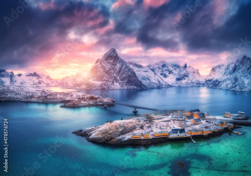 Aerial view of snowy islands with houses, rorbu, blue sea, mountains, bridge and colorful cloudy sky at sunset in winter Fototapet