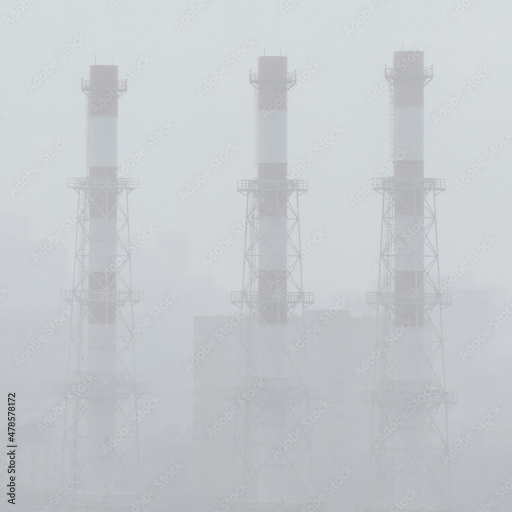 Obraz premium A city in the rain. The pipes of the factory. Factory chimneys in a white fog. The pipes of the factory. Poor visibility. Soft focus.