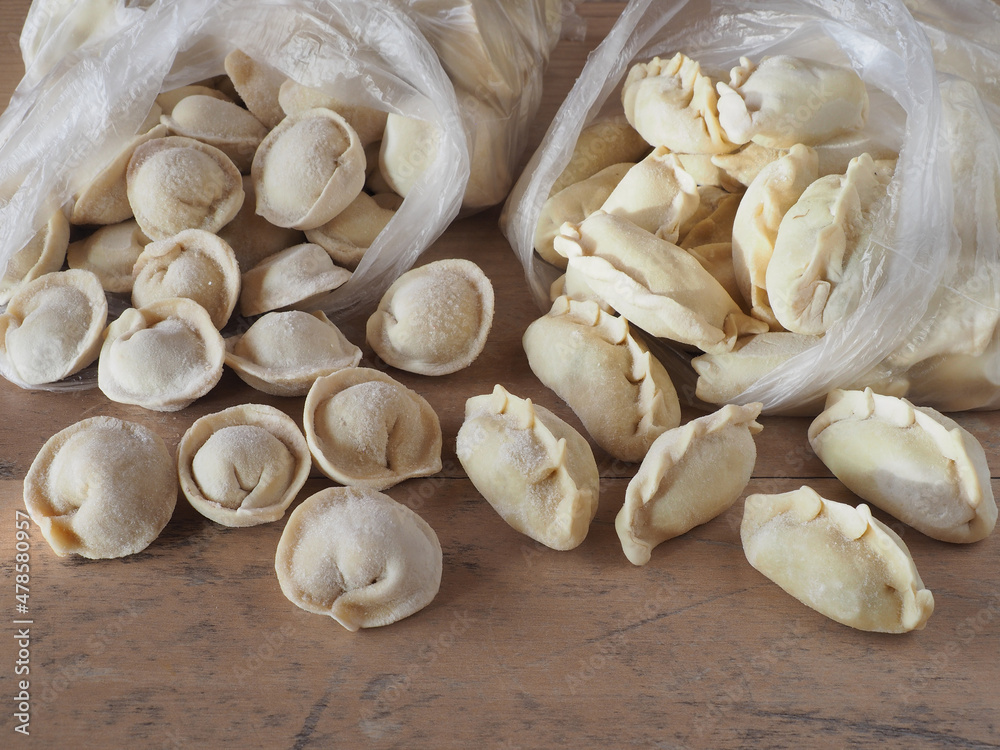 Different frozen raw dumplings and varenik with packaging on a table, flat layout. Traditional hot lunch dish, dough stuffed with meat and vegetables Different frozen raw dumplings and varenik with packaging on a table, flat layout. Traditional hot lunch dish, dough stuffed with meat and vegetables