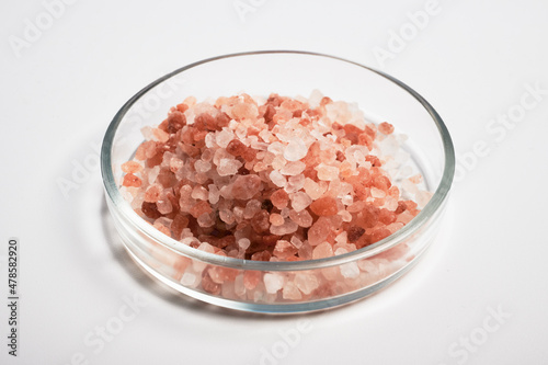 Pink colored salt inside glass petri dish. Pink Himalayan salt for cooking under closeup research. Rose salt crystals inside glass petri dish. Himalayan rock coarse salt in a flat Petri dish. Natural