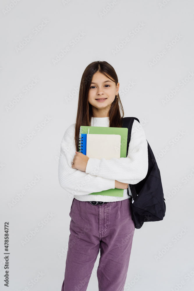 Portrait of teenager girl with school backpack holding colored folders on white background Portrait of teenager girl with school backpack holding colored folders on white background