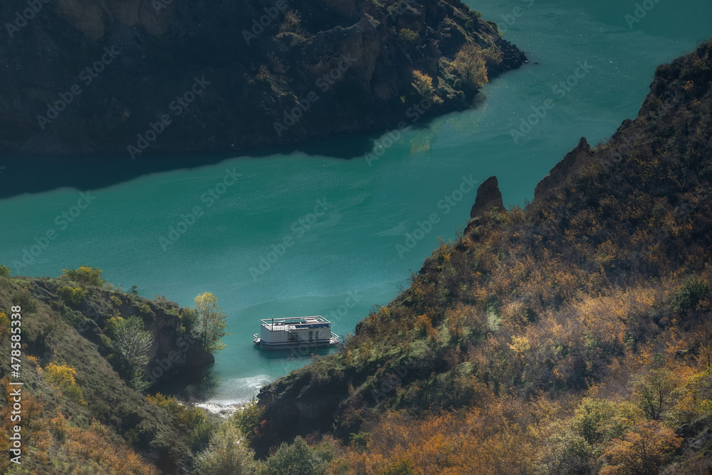 Scenic top view of the white houseboat. Emerald color of water. Sunny day. Insulation. Sulatsky canyon, Dagestan, North Caucasus