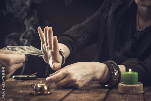 A fortune teller or oracle in search of the lines of fate in the palm of a person. Fortune telling by hand, predicting the future. Oracle refuses money