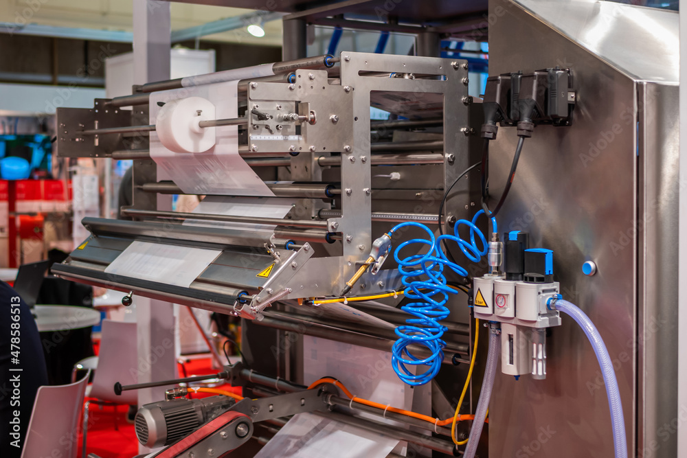 Back side of form fill and seal machine for packaging products at package exhibition, trade show. Manufacturing, industry and automated technology equipment concept Back side of form fill and seal machine for packaging products at package exhibition, trade show. Manufacturing, industry and automated technology equipment concept