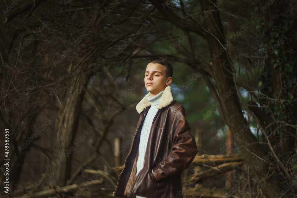 young teenager stands in the woods in late December