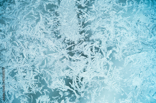 The texture is frozen glass, the background of the frost pattern is blue. Snowflakes on the glass