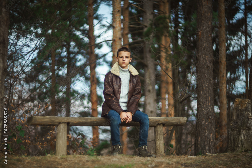 sad boy sitting on a wooden bench in the park sad boy sitting on a wooden bench in the park