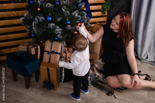 little toddler boy with woman near christmas tree and decoration. son and mother on christmas eve. new year. single mother. incomplete family.