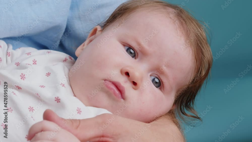 Closeup portrait of curious caucasian cute little baby with blue eyes looks around in the arms of his father. Loving and caring young father lulls his child to sleep Closeup portrait of curious caucasian cute little baby with blue eyes looks around in the arms of his father. Loving and caring young father lulls his child to sleep