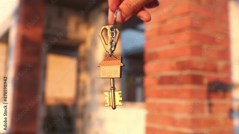 Hand with the key to the future house on the background of a construction site and walls made of porous concrete block. Building a home, moving to a new cottage, farm in the countryside