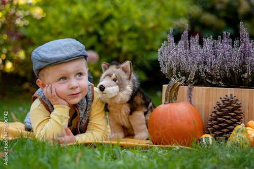 A pensive little boy lies on a blanket with his stuffed dog friend.