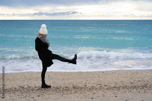 une jeune femme , sur une plage donne un cop de pied dans le sable de colère photo