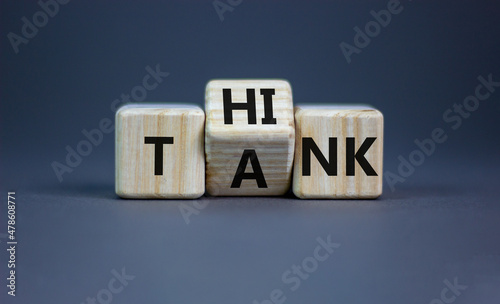 Think tank symbol. Businessman turns a wooden cube and changes the word tank to think. Beautiful grey table, grey background, copy space. Business and think tank concept.