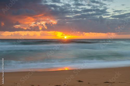 Sunrise at the seaside with waves and clouds