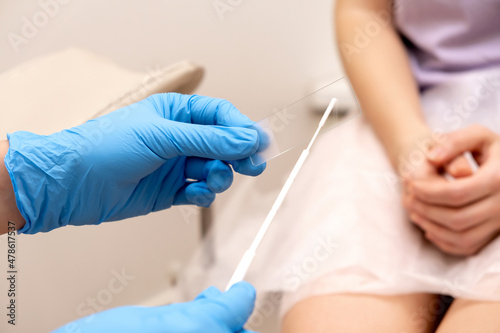 The gynecologist puts a smear on a slide glass for microscopy, hands close-up.Diagnosis of diseases of the genitourinary system.Women's health, medical concept.Selective focus. photo