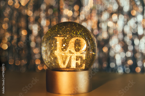 Valentine's day background. Glitter globe with word LOVE on the golden shining bokeh background. Selective focus. Copy space.