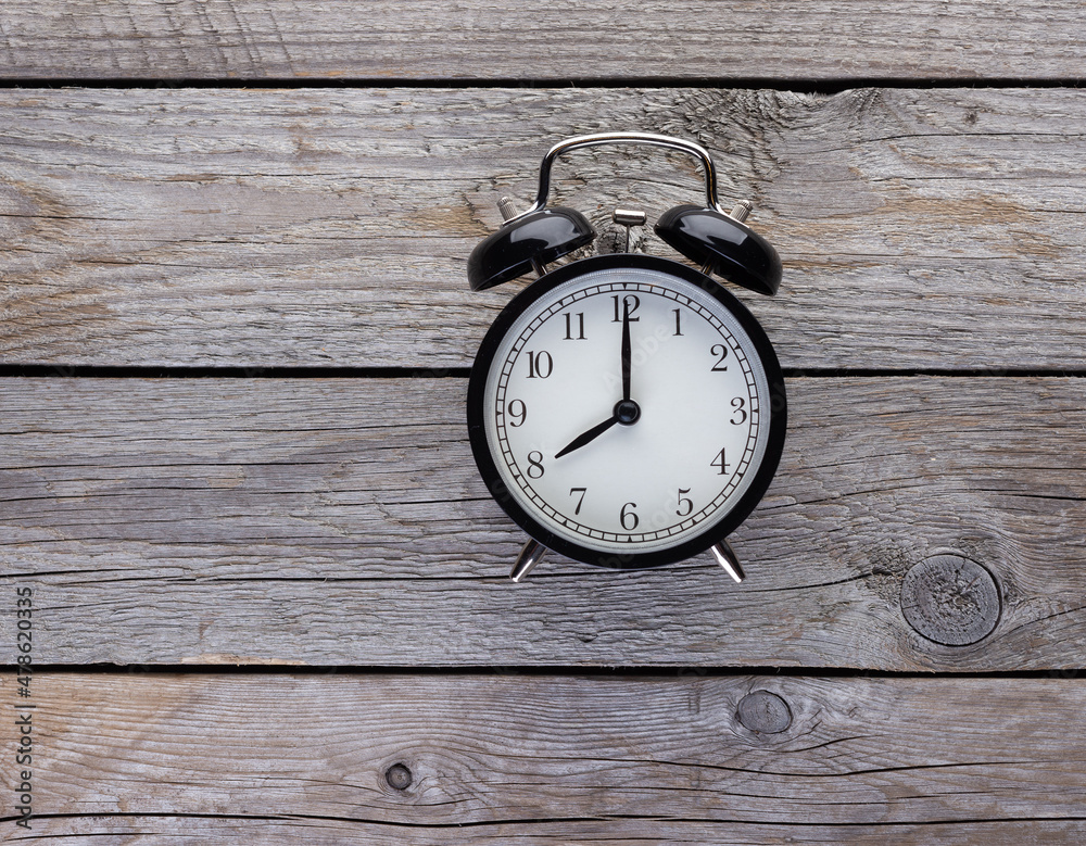 Black retro alarm clock closeup top view on wooden background. Time, deadline and morning routines concept Black retro alarm clock closeup top view on wooden background. Time, deadline and morning routines concept