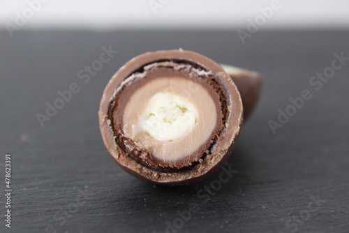 Foto Chocolate round candy sphere with layered white and dark chocolate in section
