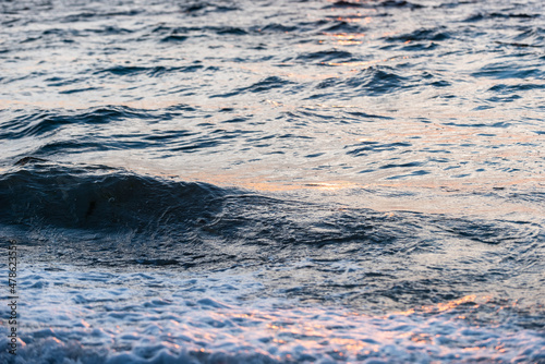 Light hits choppy ocean waves at sunset