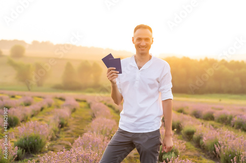 Happy young tourist man holding passport in lavender field