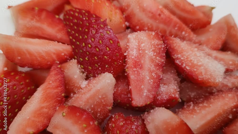 Woman sprinkles strawberries with sugar. Pieces of juicy fragrant strawberries. Strawberries in sugar. Close-up.