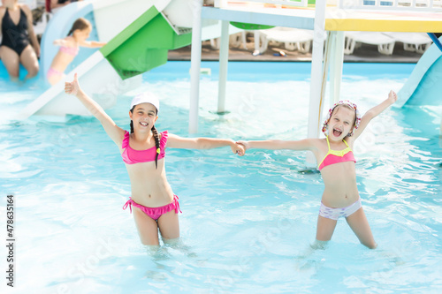 Two little girls fun jumping into the swimming pool