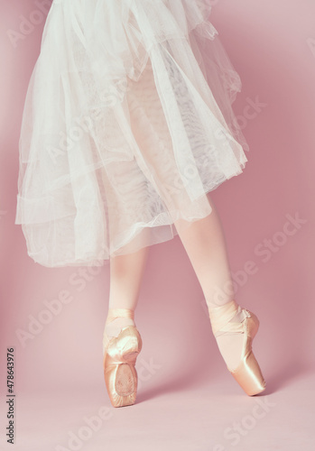 classic ballet dancer feet with stockings and white skirt on tiptoe on pink background