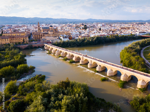Scenic aerial view of ancient Roman bridge across Guadalquivir river and Moorish architecture of Mezquita-Catedral on background with Cordoba cityscape, Spain © JackF