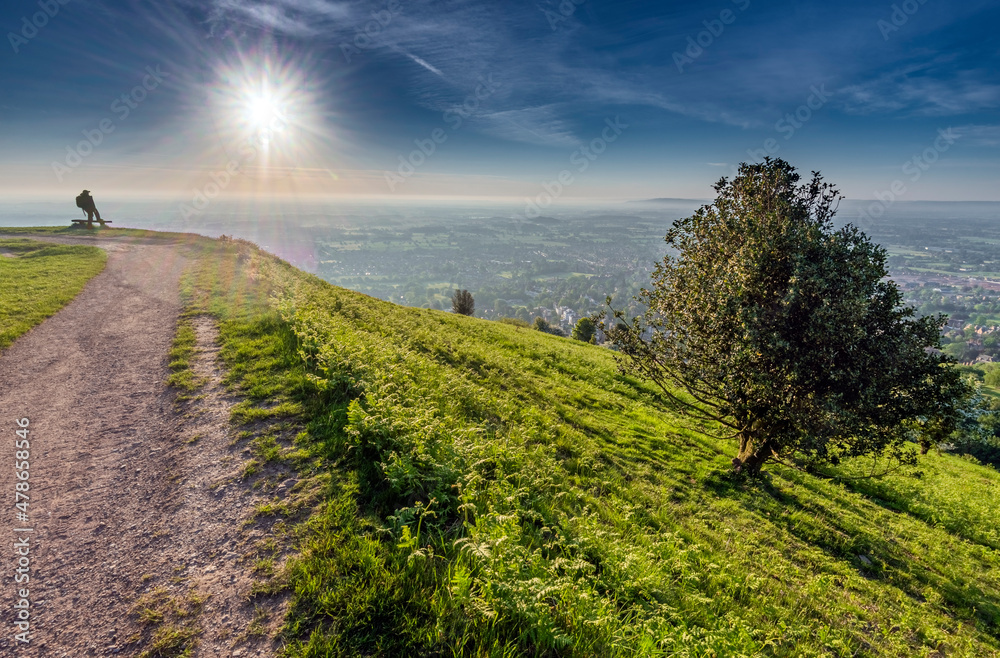 A man watches the sun rise from the Malvern Hills,Worcestershire,England.