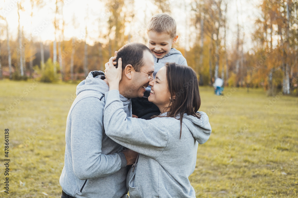 MIddle-aged parents with their little son standing in the park outdoors. Family day. MIddle-aged parents with their little son standing in the park outdoors. Family day.