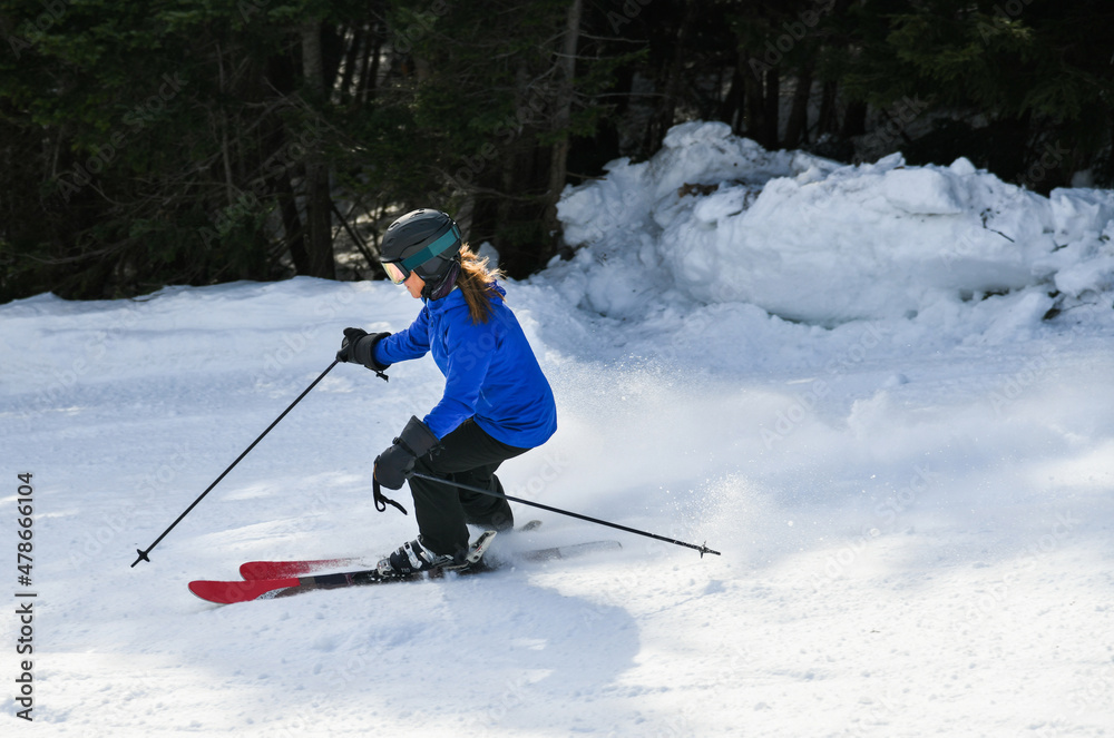 Female skier in bright blue jacket riding downhill on fresh powder snow. Sport and lifestyle concept. Female skier in bright blue jacket riding downhill on fresh powder snow. Sport and lifestyle concept.