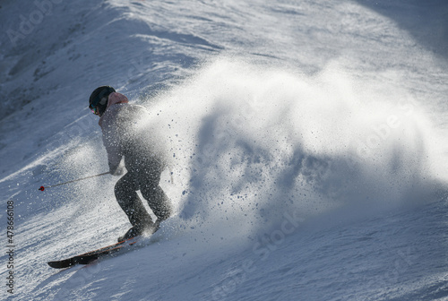 Male skier going downhill on a high speed leaving fresh powder snow behind. Active lifestyle and sport concept. Beautiful winter day at Stowe Ski Resort, Vermont.