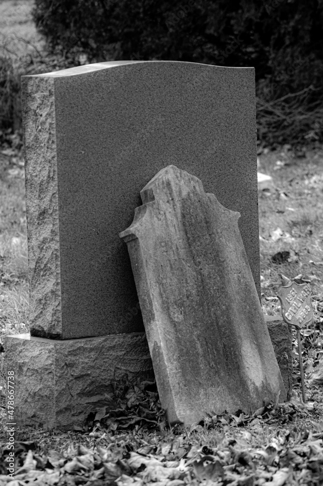 Headstone leaning against a headstone. Black and white. Stock Photo