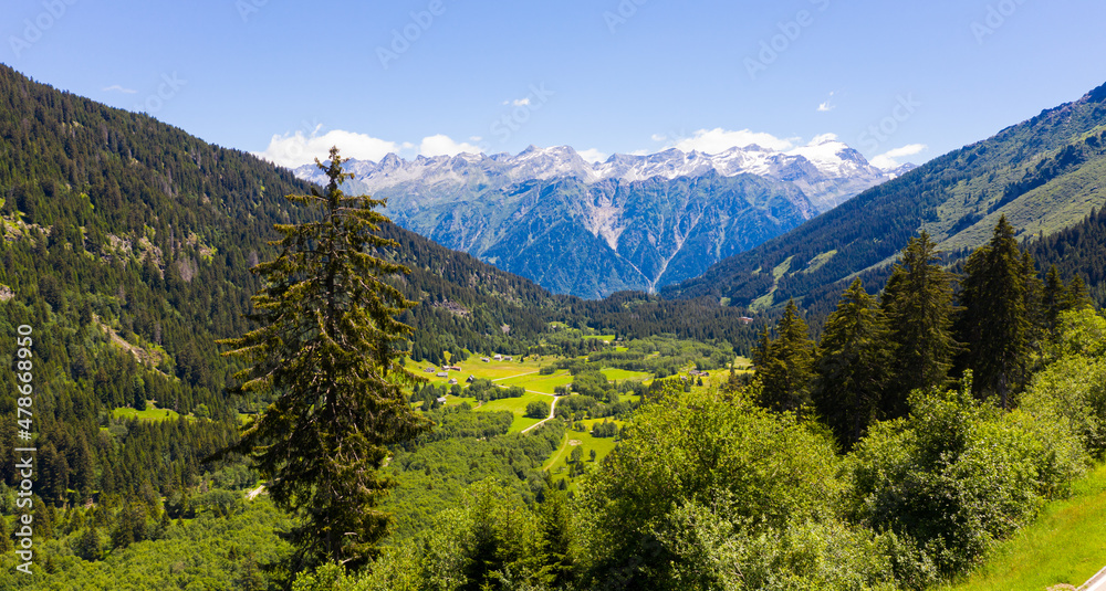 Unique summer Alpine landscape in Swiss canton of Grisons with rocky mountain ranges and greenery on foothills