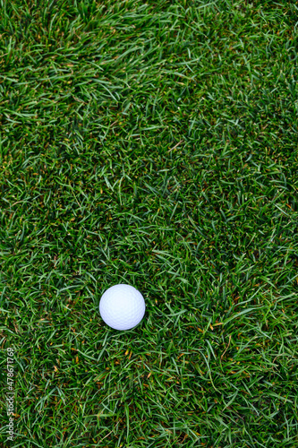 Lush green golf course grass in the rough, with a white golf ball ready to play 