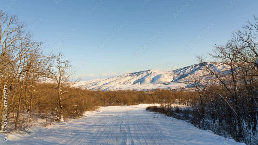 Snow covered road between mountain forest Snow covered road between mountain forest