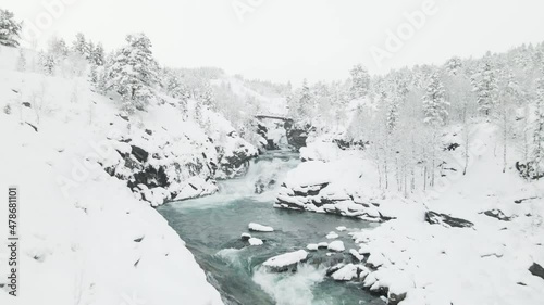 Rocky River Flowing Into Snowy Forest During Winter With Bridge In Billingen Mesa In Sweden. - aerial photo