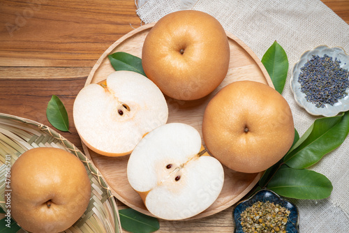 Premium Korean Sweet Pear with slice in wooden plate, Fresh Nashi pear or Korean pear fruit in wooden plate on wooden background. photo