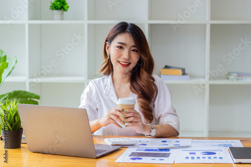 Businesswoman analyzing company sales in past years, woman sitting in chair holding coffee cup looking at financial documents on desk, accountant checking company numbers, new business concept.