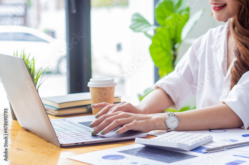 Businesswoman typing company sales data on computer, woman sitting in a chair looking at financial documents on desk, accountant checking company numbers, modern businessman concept.