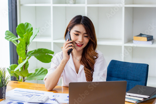 Businesswoman discussing company sales data last year on the phone, woman sitting in a chair looking at financial documents, accountant checking company numbers, concept of modern business people.