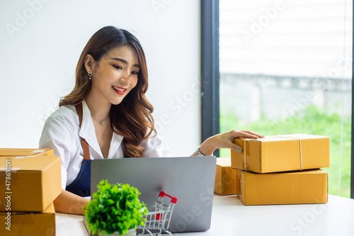 An online business owner checks the name and address of a customer ordering a company product, Cropped photo of a woman checking and writing the name on a parcel for delivery at an online sale office.